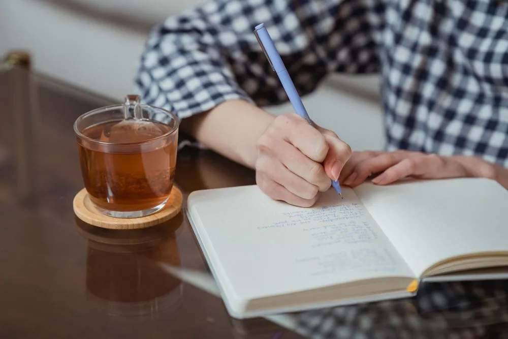 ノートに書く手元とお茶